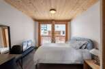 Experience the charm of this cozy bedroom, featuring a warm wooden ceiling and a comfortable bed.
