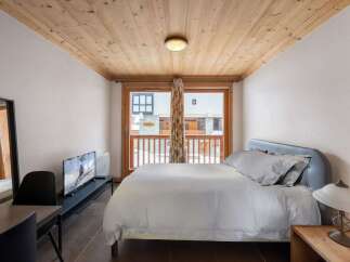 Experience the charm of this cozy bedroom, featuring a warm wooden ceiling and a comfortable bed.