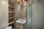 This charming bathroom features a pedestal sink, a large mirror with a wooden frame, and a convenient shower.