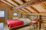 Step into rustic charm with this cozy bedroom featuring exposed wooden beams and a warm, inviting atmosphere.