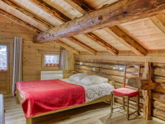 Step into rustic charm with this cozy bedroom featuring exposed wooden beams and a warm, inviting atmosphere.
