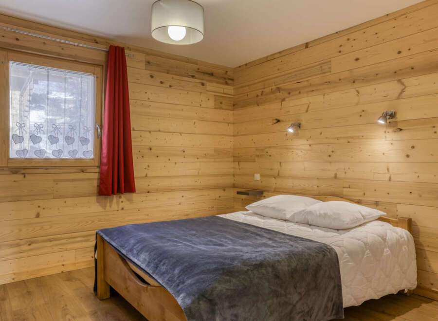 This cozy bedroom features beautiful wooden walls and flooring, creating a warm and inviting atmosphere.