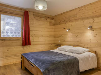 This cozy bedroom features beautiful wooden walls and flooring, creating a warm and inviting atmosphere.