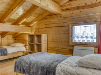 This cozy cabin bedroom features a warm, inviting atmosphere with its wooden walls and ceiling.
