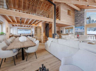 Experience luxury living in this stunning chalet, featuring a spacious open-plan design with exposed wooden beams and a cozy fireplace.