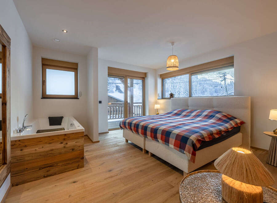 Experience luxury in this stunning bedroom featuring a cozy bed with a vibrant plaid comforter.