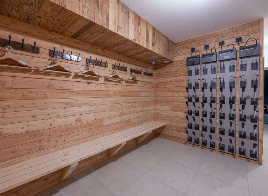 This ski room features a warm, inviting atmosphere with its wooden paneling and a convenient bench for putting on and taking off boots.