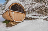 Experience the ultimate relaxation in this stunning barrel sauna nestled in a snowy landscape.