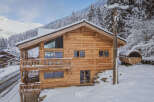 Experience the ultimate winter getaway in this stunning wooden chalet nestled in a snowy mountain landscape.