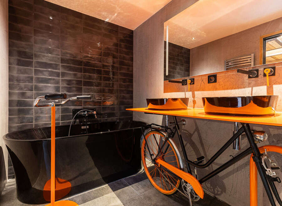 This unique bathroom design features a striking black bathtub and a creative sink setup.