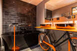 This unique bathroom design features a striking black bathtub and a creative sink setup.