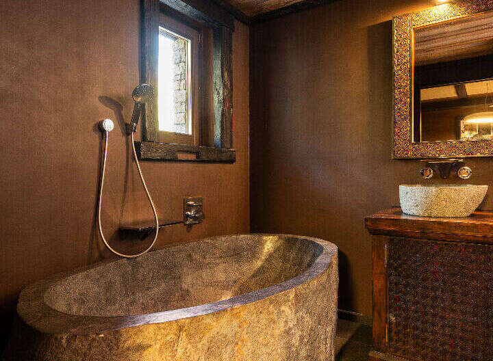 Experience rustic luxury in this stunning bathroom featuring a unique stone bathtub.