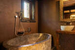 Experience rustic luxury in this stunning bathroom featuring a unique stone bathtub.