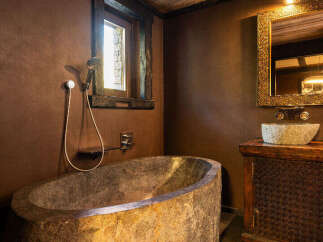 Experience rustic luxury in this stunning bathroom featuring a unique stone bathtub.