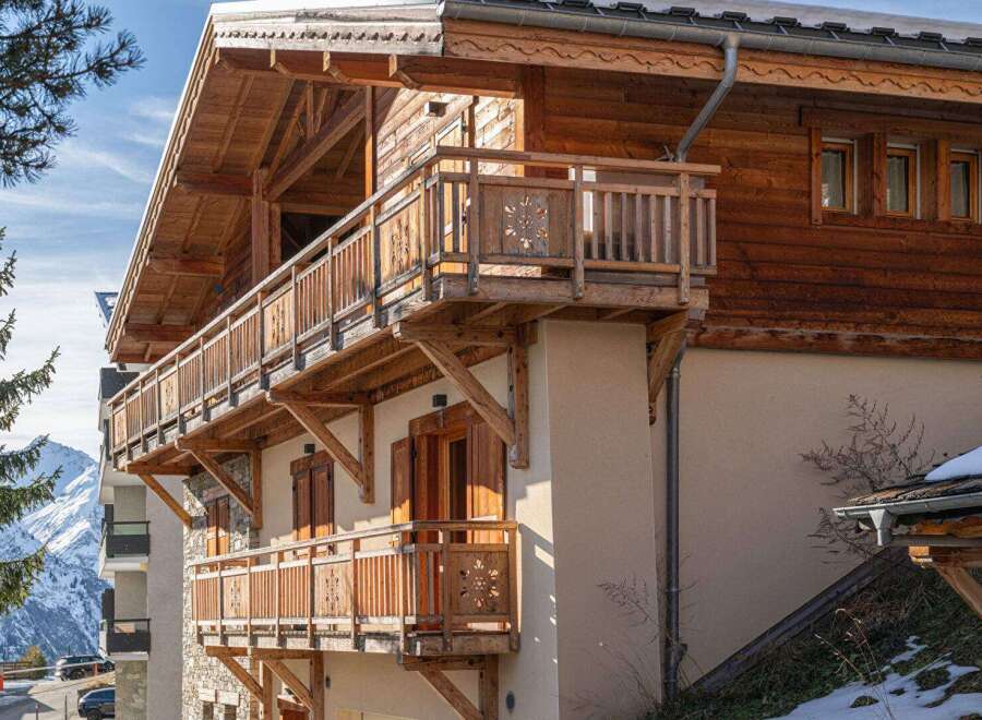 This stunning chalet boasts exquisite wooden balconies and a charming architectural design, perfect for a luxurious mountain retreat.
