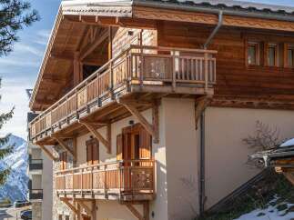 This stunning chalet boasts exquisite wooden balconies and a charming architectural design, perfect for a luxurious mountain retreat.