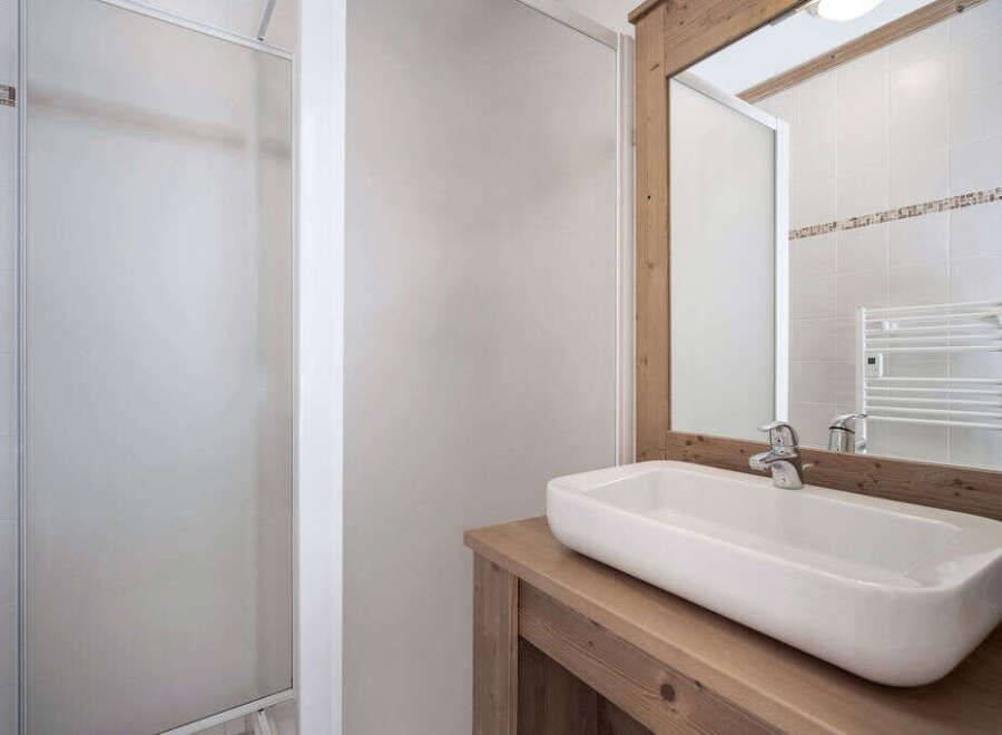 This modern bathroom features a sleek, rectangular sink set atop a rustic wooden vanity.