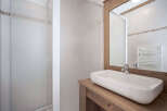 This modern bathroom features a sleek, rectangular sink set atop a rustic wooden vanity.