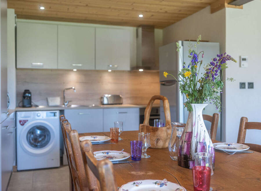 This charming kitchen and dining area features a modern aesthetic with light-colored cabinetry and a wooden ceiling.