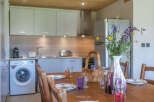 This charming kitchen and dining area features a modern aesthetic with light-colored cabinetry and a wooden ceiling.