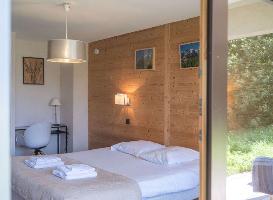 Experience serene mountain living in this charming bedroom featuring a cozy bed adorned with crisp white linens and plush pillows.