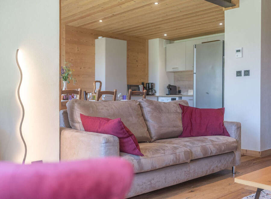 Experience modern alpine living in this beautifully appointed living space, featuring a comfortable sofa adorned with plush crimson pillows.