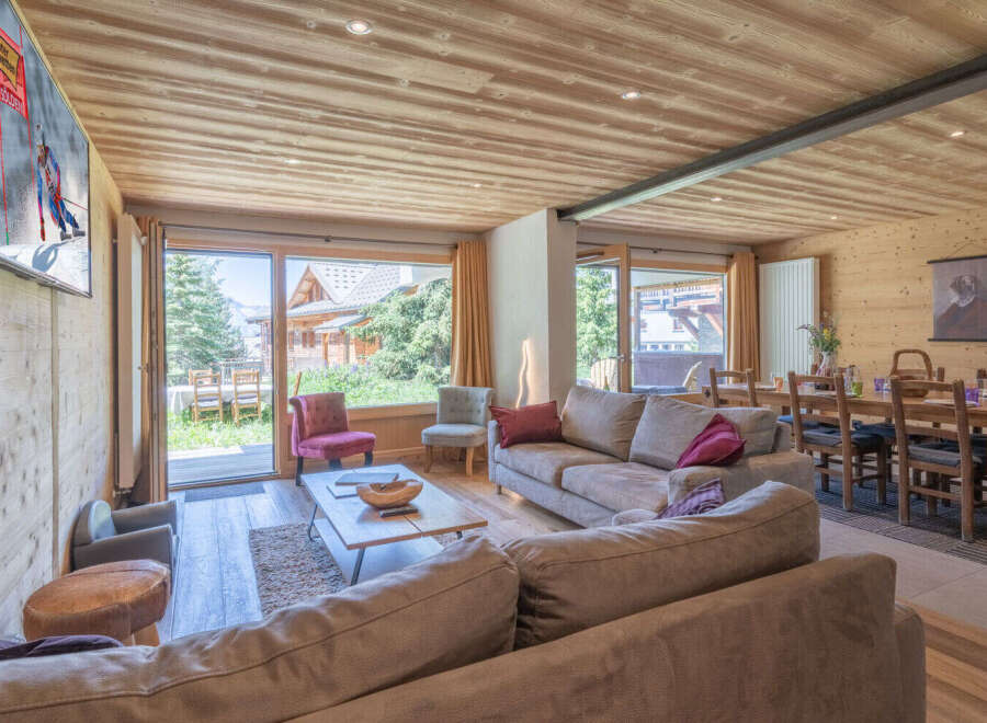 Experience luxury mountain living in this stunning chalet, featuring a spacious open-plan living area with a cozy fireplace and large windows offering breathtaking views.