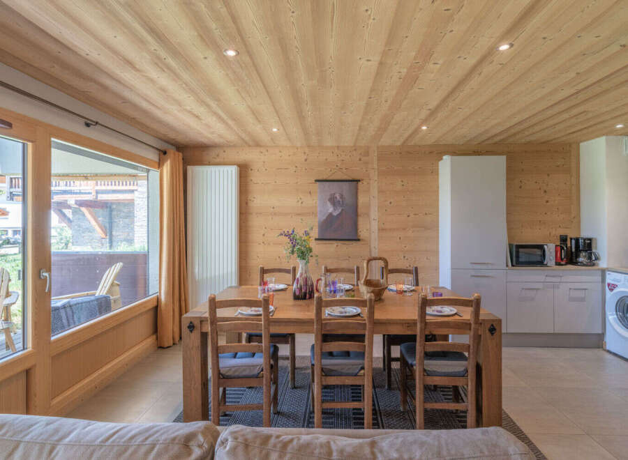 Experience cozy living in this charming wooden interior featuring a spacious dining area with a rustic wooden table and chairs, perfect for family meals.