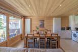 Experience cozy living in this charming wooden interior featuring a spacious dining area with a rustic wooden table and chairs, perfect for family meals.