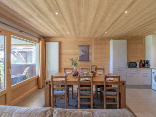 Experience cozy living in this charming wooden interior featuring a spacious dining area with a rustic wooden table and chairs, perfect for family meals.