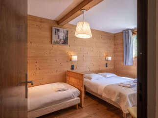 This charming bedroom features warm wooden walls and a cozy ambiance, perfect for a relaxing retreat.