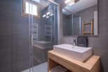 Experience modern comfort in this stylish bathroom featuring a spacious walk-in shower with sleek grey tiling and a convenient heated towel rack.
