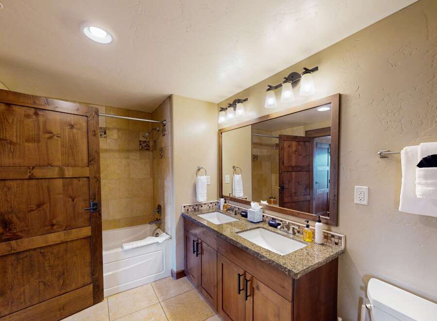 This stunning bathroom features a double vanity with a granite countertop, offering ample space for your daily routines.