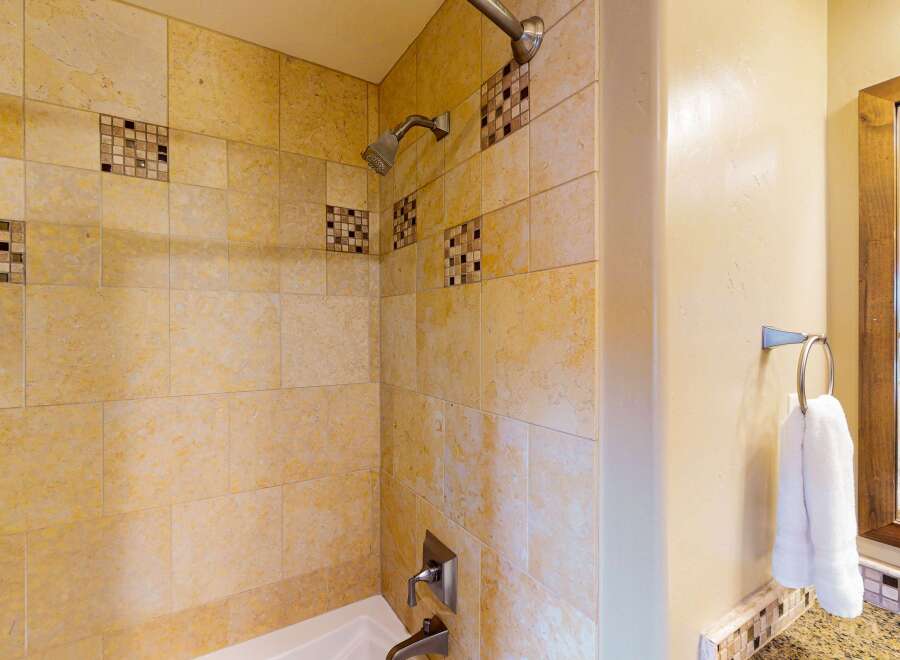 Step into a beautifully designed bathroom featuring elegant tile work and a modern shower head.
