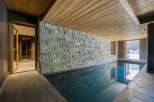 This stunning indoor pool features a beautiful stone wall and wooden ceiling, creating a luxurious and relaxing atmosphere.