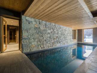 This stunning indoor pool features a beautiful stone wall and wooden ceiling, creating a luxurious and relaxing atmosphere.