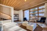 Experience luxury living in this stunning property, featuring a cozy living room with a wooden ceiling and large windows that offer breathtaking views of the snowy landscape.