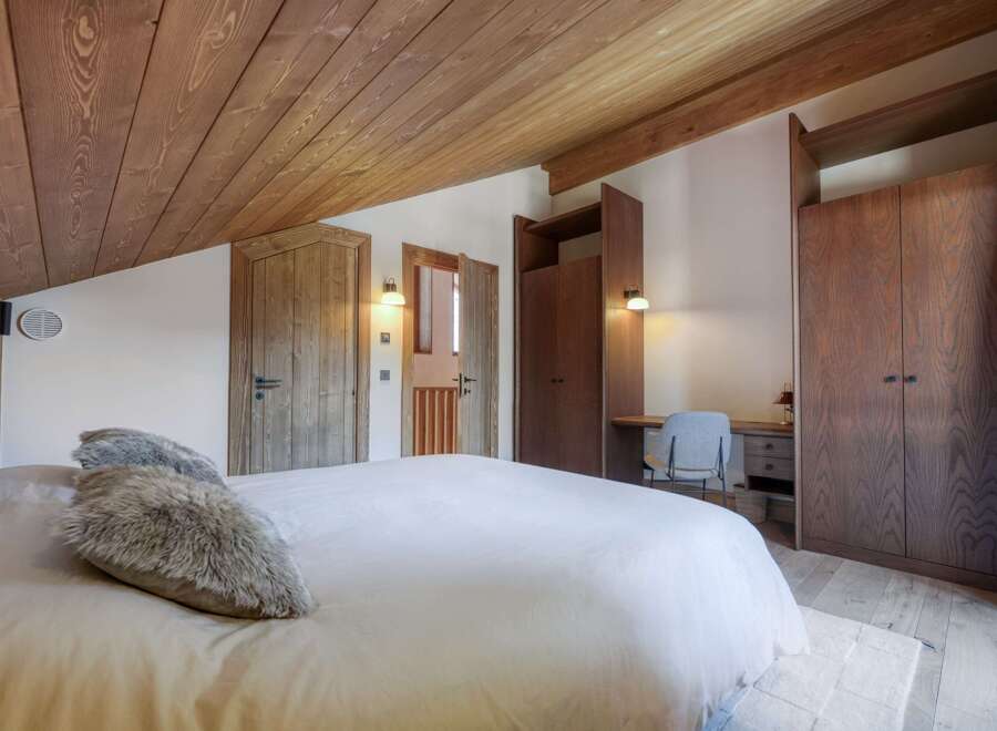 This stunning bedroom boasts a warm and inviting ambiance with its wooden ceiling and walls.