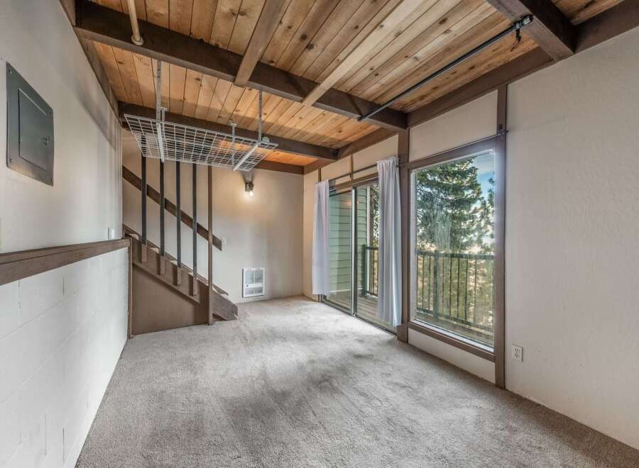 Discover the charm of this inviting living space, featuring a unique wooden ceiling and a cozy carpeted floor.
