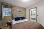 Discover the charm of this cozy bedroom, featuring a rustic wooden wall and a comfortable bed with plush pillows.