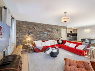 Experience luxury living in this stunning property, featuring a cozy red sofa perfect for relaxation.