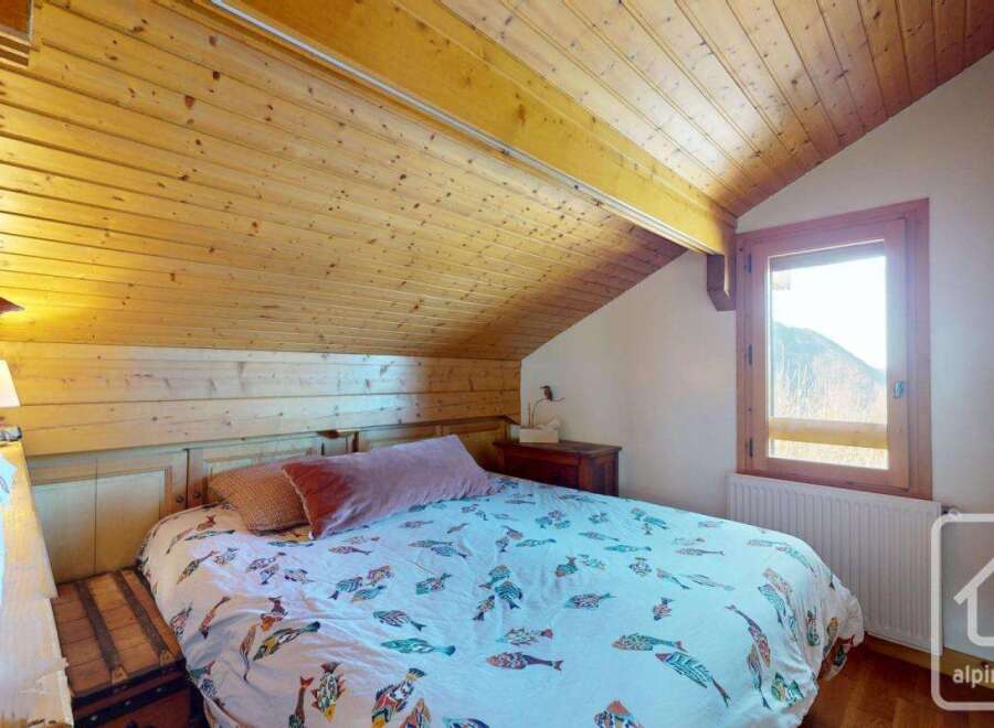 Discover the charm of this cozy bedroom, featuring a unique wooden ceiling and walls that exude warmth and character.