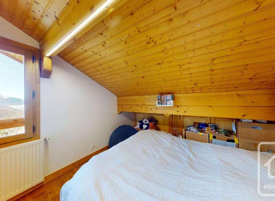 Discover the charm of this cozy bedroom featuring a unique wooden ceiling and a stunning mountain view.