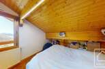 Discover the charm of this cozy bedroom featuring a unique wooden ceiling and a stunning mountain view.