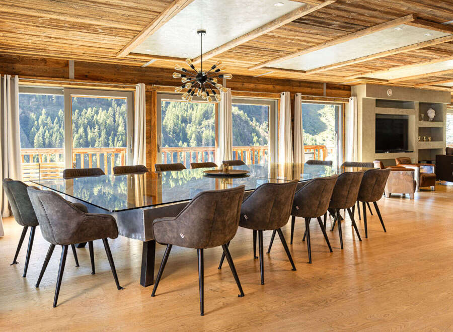 Experience luxury living in this stunning property, featuring a spacious dining area with a modern glass table and stylish chairs.