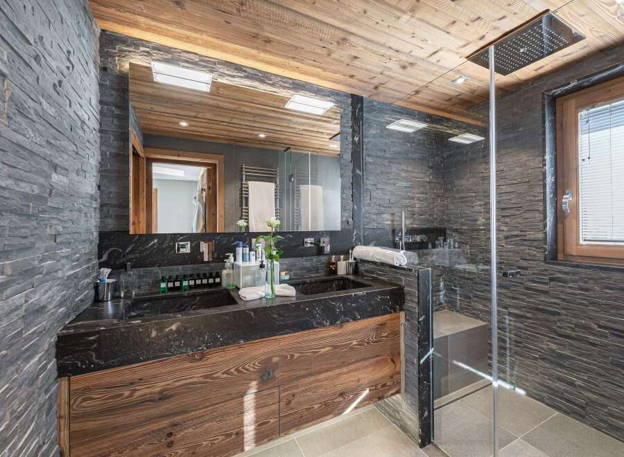 Experience luxury in this stunning bathroom featuring a sleek black marble vanity and a spacious walk-in shower.