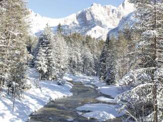 Nestled in a serene winter wonderland, this property offers breathtaking views of snow-capped mountains and a tranquil river.