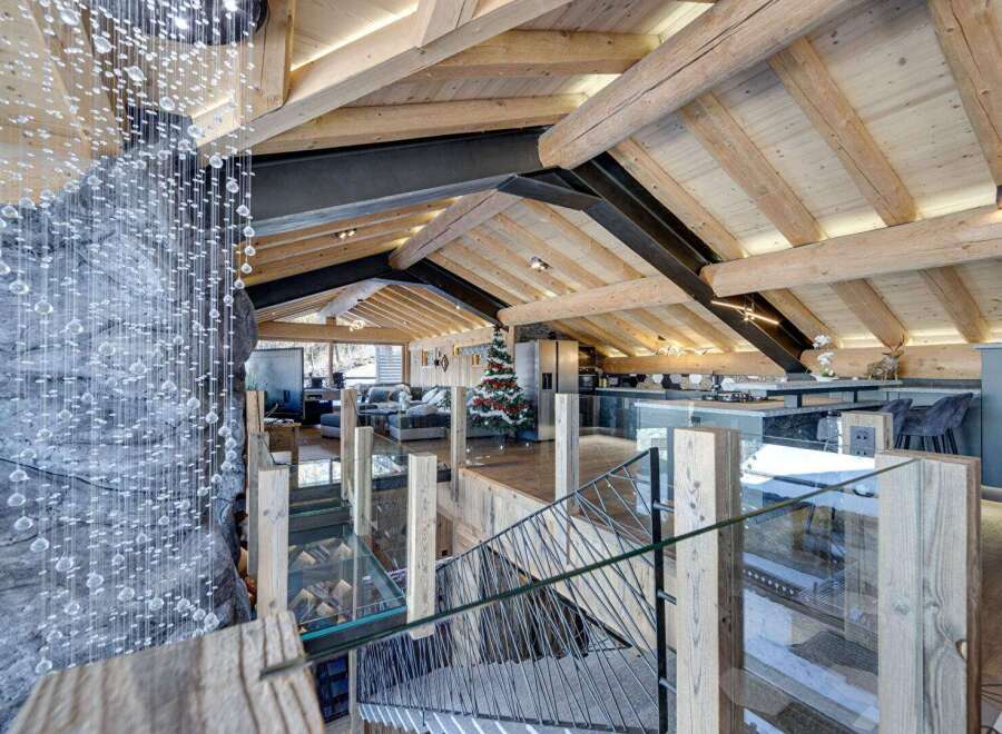 Experience luxury living in this stunning chalet, featuring a unique design with exposed wooden beams and a modern kitchen.