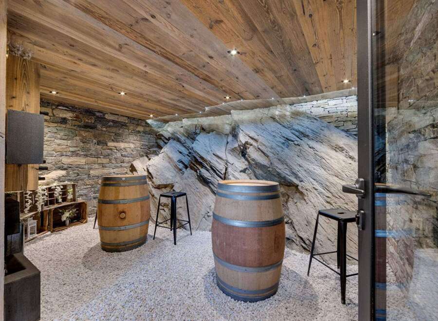 Discover the rustic charm of this unique wine cellar, featuring exposed stone walls and wooden barrel accents.