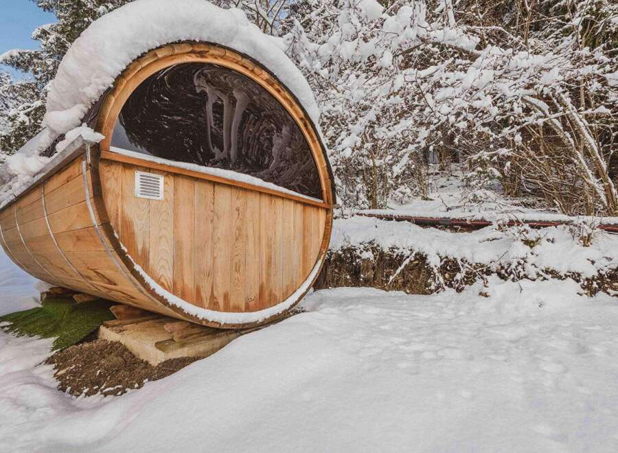 Experience the ultimate relaxation in this unique barrel sauna nestled in a snowy landscape.